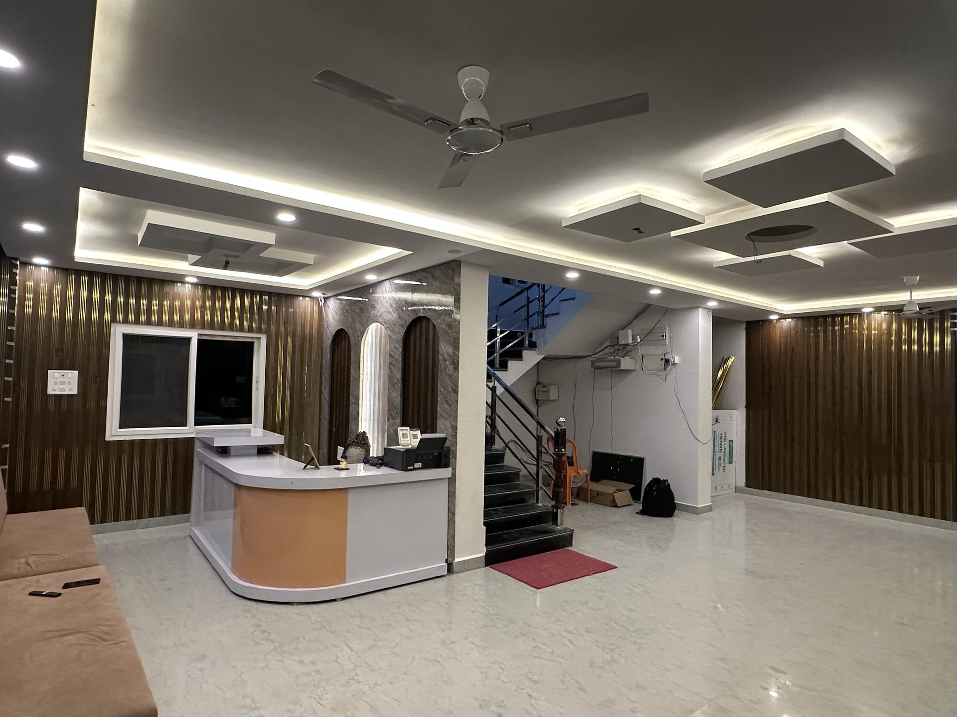 Spacious lobby with walnut slat walls, marble floor, seating area and staircase