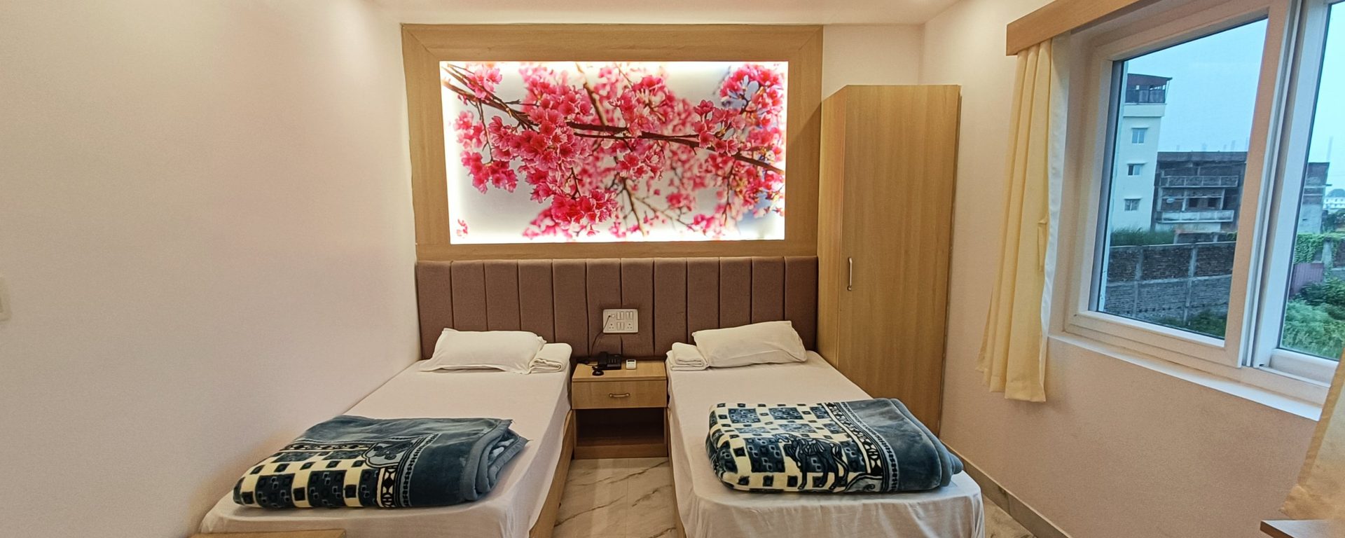 Deluxe room with two single beds beneath a backlit cherry-blossom panel, an oak wardrobe and a large window